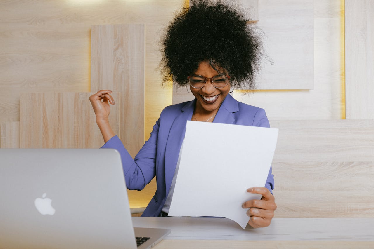 Eine Frau liest ein Testimonial über ihre Über mich Seite und freut sich sichtlich. Sie hält ein Papier in der Hand, vor ihr steht ein Laptop.