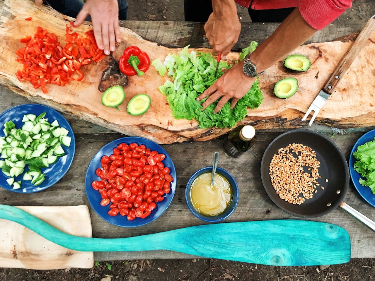 Auch gesunde Ernährung gehört zu einem achtsamen Leben. Deshalb steht hier eine Holzplatte voller gesunder Nahrung wie Paprika, Gurke, Salat, Avocado. Drei "Arme" schneiden dass Gemüse. 