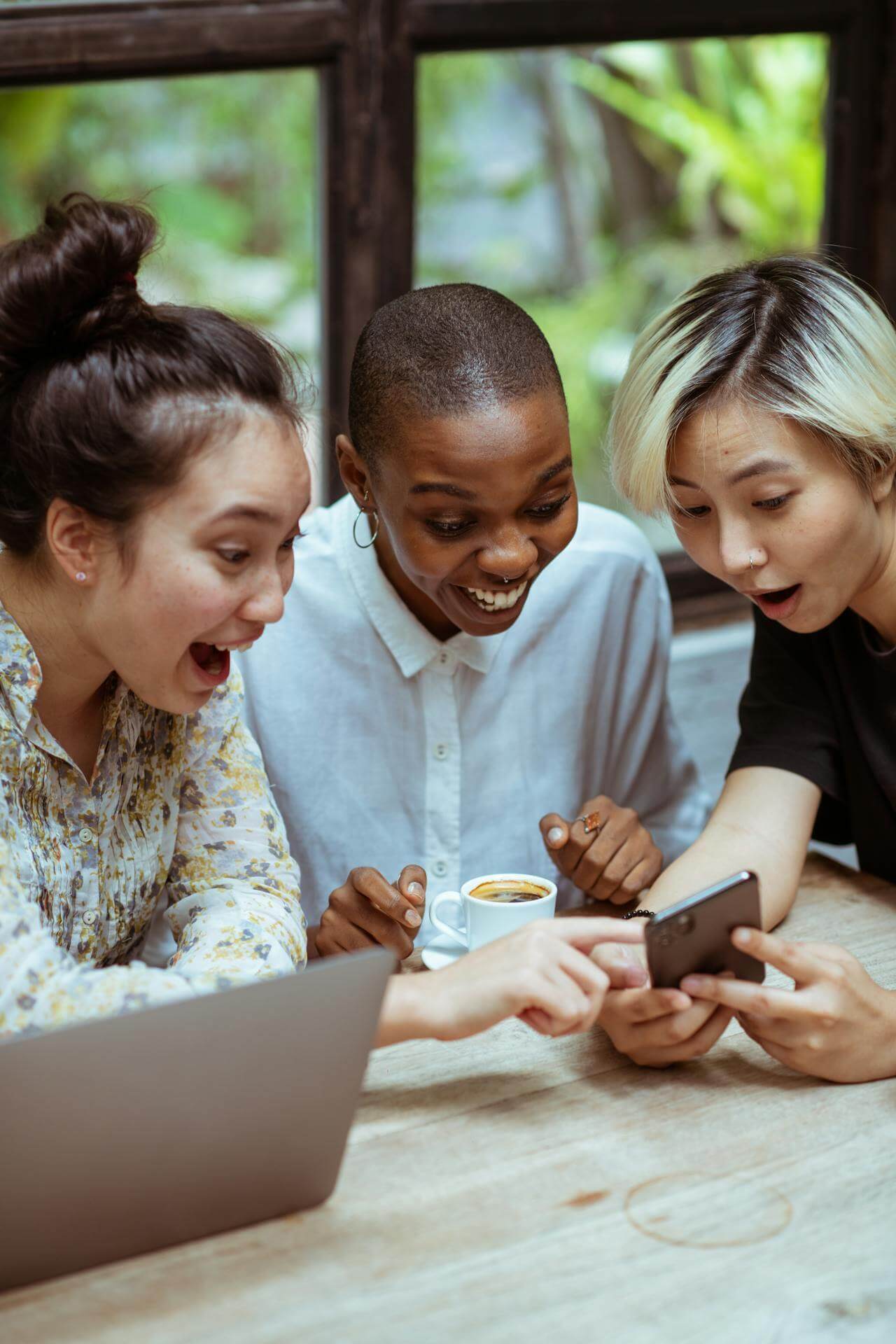 Eine Gruppe junger Menschen schaut erfreut auf ihr Handy. Sie haben die Social Media Betreuung abgegeben. 